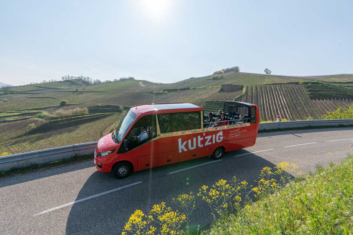 Bus cabriolet rouge qui circule dans le vignoble autour de Turckheim